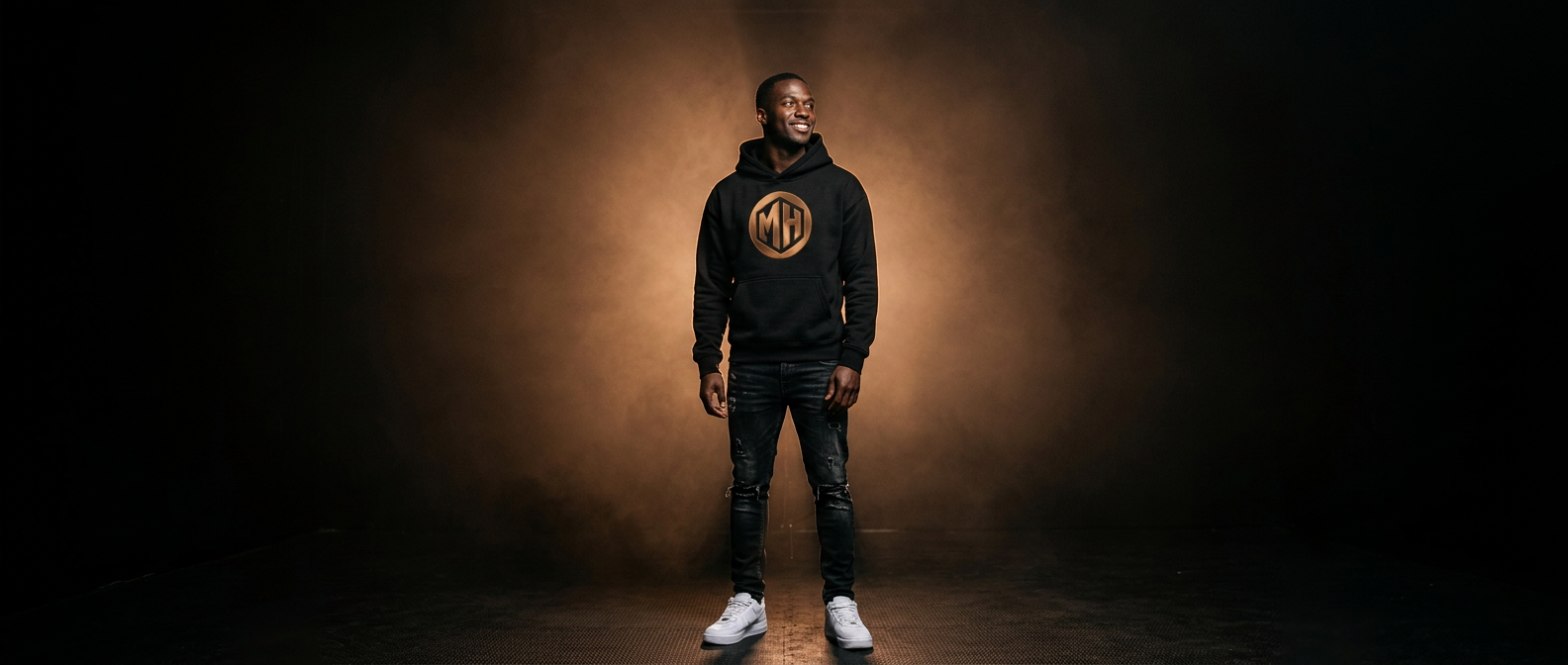 MR. HAPPINESS founder portrait — smiling model in branded hoodie under bronze studio light