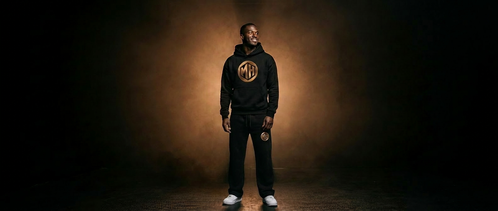MR. HAPPINESS founder portrait — smiling model in branded hoodie under bronze studio light