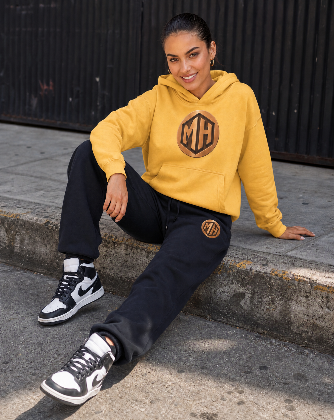 Model in MR. HAPPINESS yellow hoodie with bronze MH monogram and black joggers